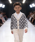 Young boy walking on a fashion show runway wearing a patterned cardigan.