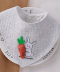 Gray baby bib with cartoon rabbit and carrot design on a white background