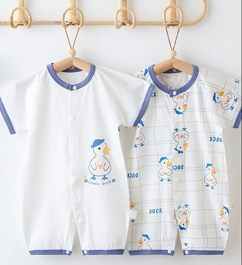 Two baby rompers with duck designs on hangers against a white wall.