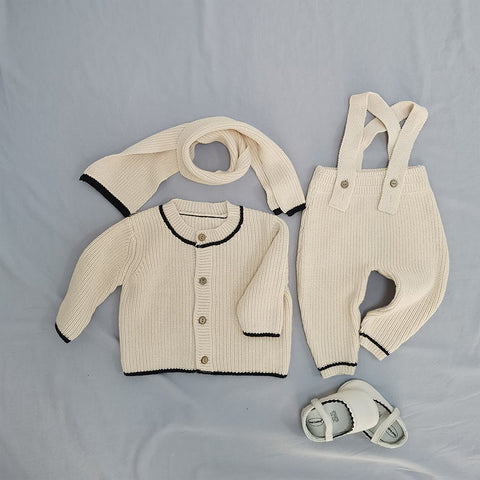 Children's knit outfit with sweater, overalls, and scarf on a gray background
