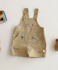Beige overalls with embroidered text and graphics on a light background