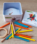 Colorful sticks with a tin container on a wooden surface