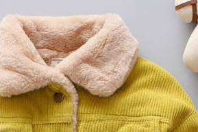 Yellow corduroy jacket with pink fleece collar on a light gray background