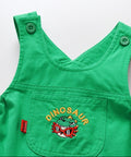 Green children's dress with dinosaur design on a white background