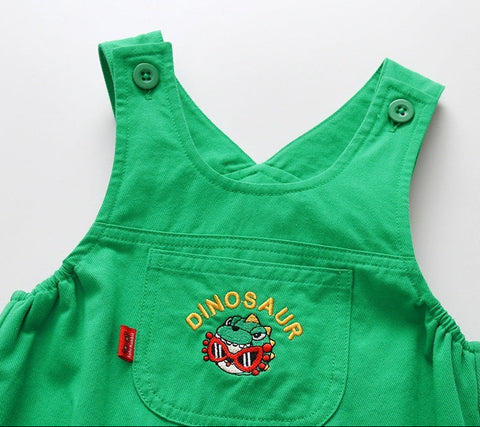 Green children's dress with dinosaur design on a white background
