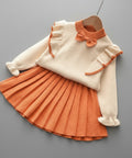 Children's outfit with white sweater and orange pleated skirt on a white background
