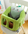 Green baby high chair with cartoon face design on a wooden floor.