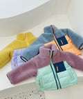 Four colorful children's jackets arranged on a white surface.