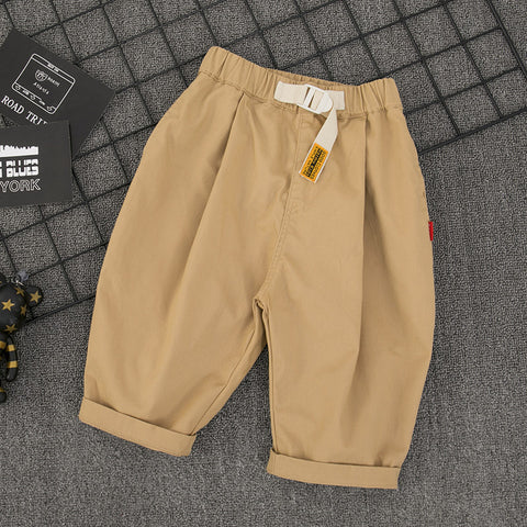 Beige pants with a tag on a textured gray surface