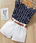 Children's outfit with floral top and white shorts on a wooden surface