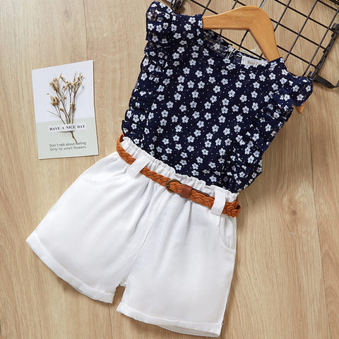Children's outfit with floral top and white shorts on a wooden surface