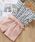 Pink fabric with a bow and patterned fabric on a wooden surface