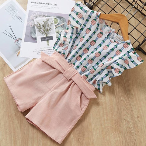 Pink fabric with a bow and patterned fabric on a wooden surface