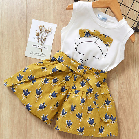 Children's outfit with white top and yellow shorts on a wooden surface