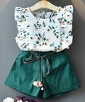 Children's outfit with floral top and green shorts on a gray background