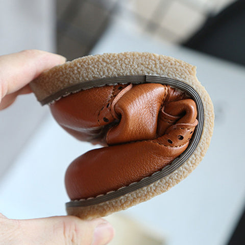 Brown leather glove inside a circular container held by a hand on a light background