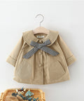 Beige children's coat with a checkered bow on a hanger against a white background
