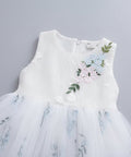 White dress with floral embroidery on a hanger against a gray carpet background