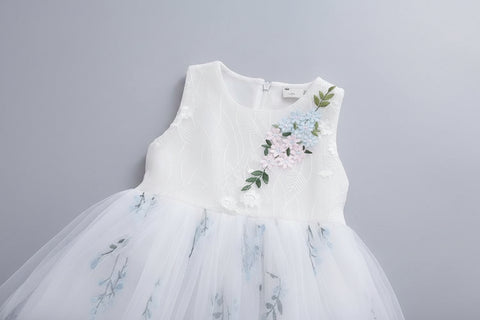 White dress with floral embroidery on a hanger against a gray carpet background
