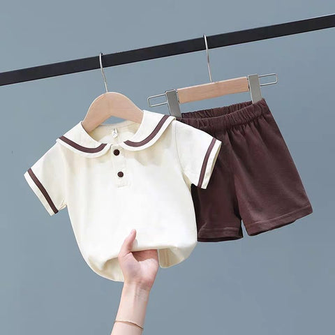 Children's outfit with white shirt and brown shorts on hangers against a gray background