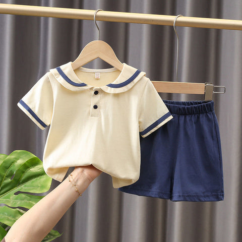 Children's outfit with beige shirt and navy shorts on a hanger against a neutral background.