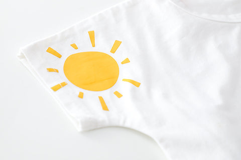 White pillow with a yellow sun design on a white background