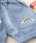Light blue denim shorts with a rainbow and cloud design on a light background