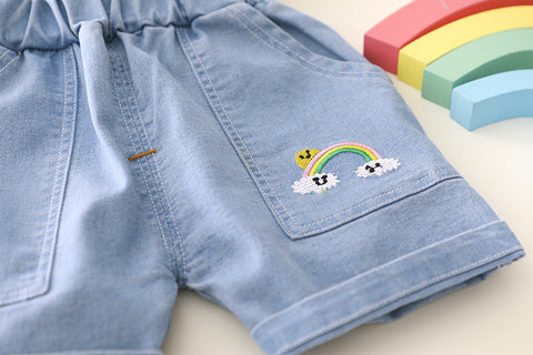 Light blue denim shorts with a rainbow and cloud design on a light background