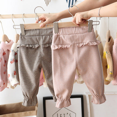 Two pairs of baby pants on hangers with a neutral background