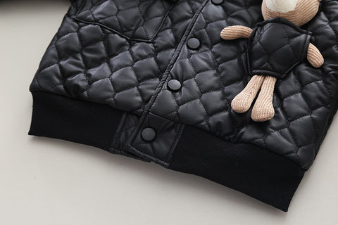 Black quilted jacket with a small plush toy on a light background