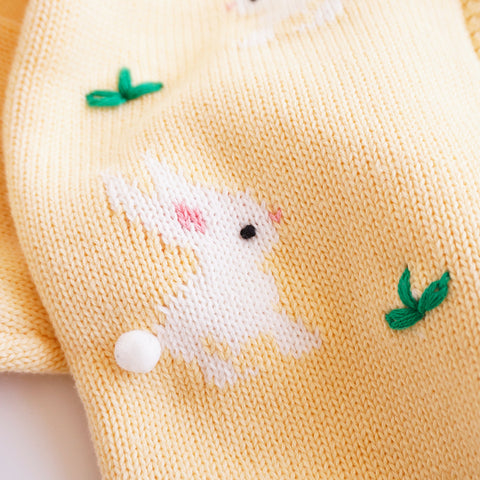 Yellow fabric with embroidered white rabbit and green leaves on a plain background