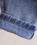 Close-up of a blue denim fabric with a rolled hem on a light background