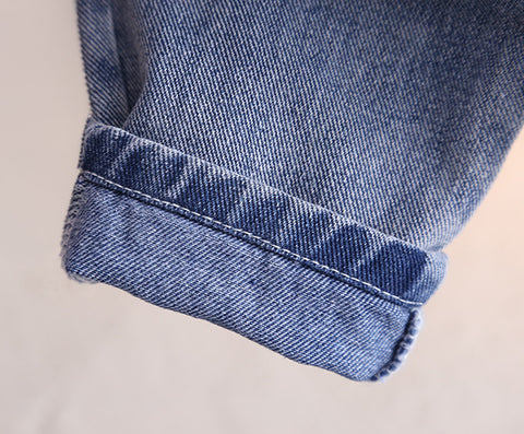 Close-up of a blue denim fabric with a rolled hem on a light background