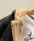Close-up of a denim jacket with beige fleece lining on a hanger against a neutral background