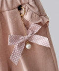 Pink polka dot bow keychain with a pearl on a pink textured background