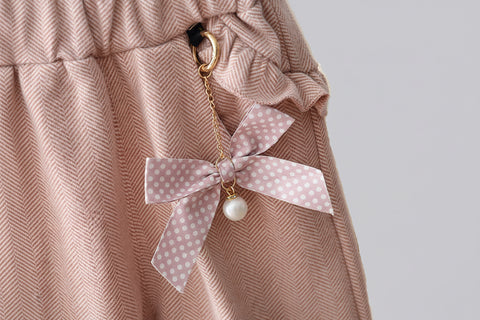 Pink polka dot bow keychain with a pearl on a pink textured background