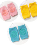 Set of colorful baby knee pads with smiley face designs on a white background