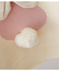 Close-up of a soft toy with pink heart and white pom-pom on a light background