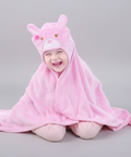 Baby wrapped in a pink hooded towel with bear ears on a gray background