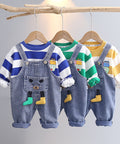 Three children's outfits with denim overalls and colorful shirts on hangers against a gray background.