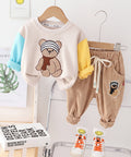 Children's clothing set with teddy bear design on a hanger against a white wall.
