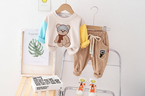 Children's clothing set with teddy bear design on a hanger against a white wall.