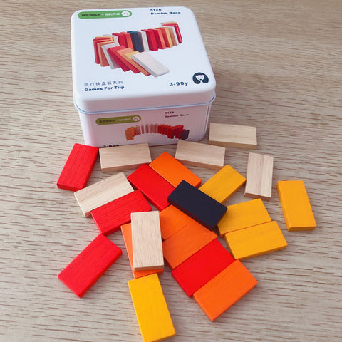 Colorful wooden blocks with a tin box labeled 'Games For Trip' on a wooden surface.