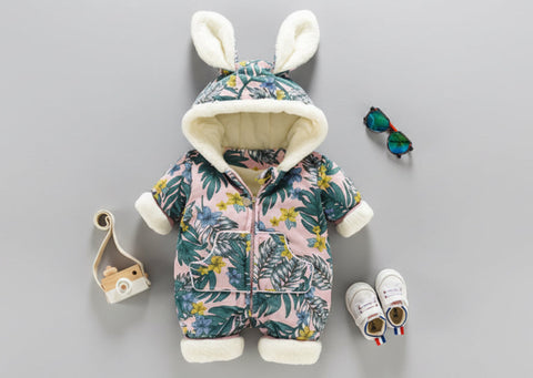 Floral baby snowsuit with bunny ears, baby shoes, and booties on a gray background