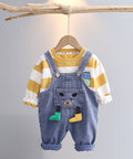 Children's outfit with striped shirt and denim overalls on a hanger against a gray background
