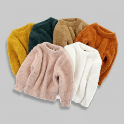 Set of five different colored fluffy sweaters on a white background