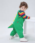 Child wearing a green dinosaur costume with a rainbow shirt on a white background