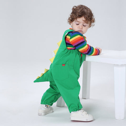 Child wearing a green dinosaur costume with a rainbow shirt on a white background