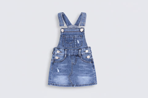 Blue denim overall dress on a white background
