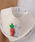 White baby bib with cartoon rabbit and carrot design on a white background
